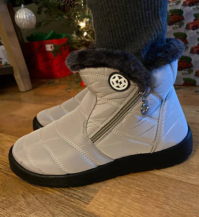 a reviewer wearing the ankle snow boots in gray, with black fur lining
