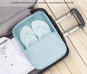 the blue shoe pouch holding a pair of flip flops inside a suitcase