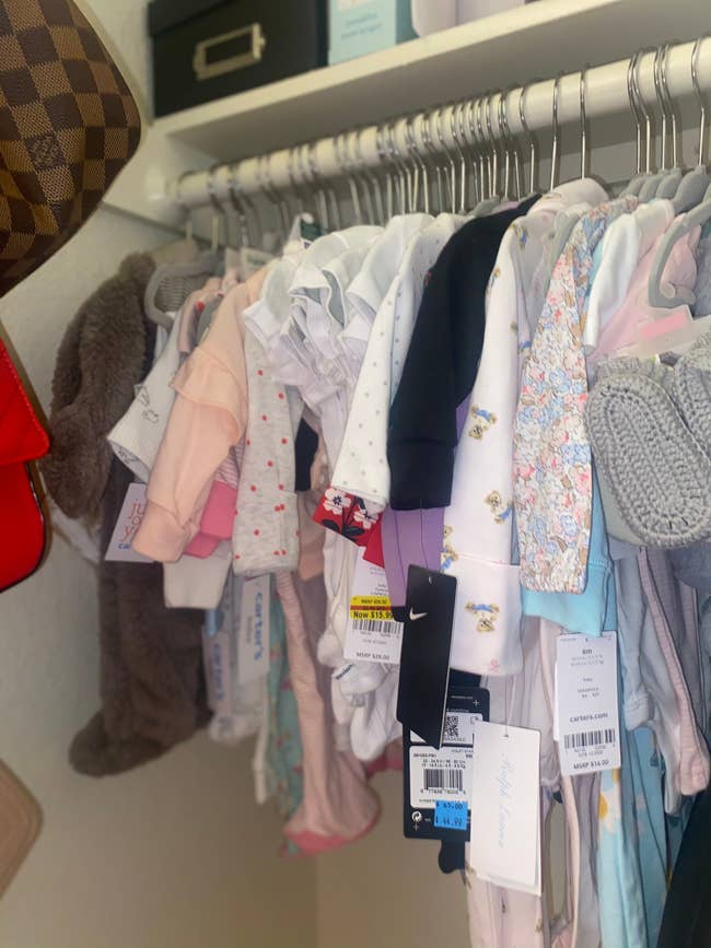 a reviewer photo of baby clothes hanging on the hangers in a closet