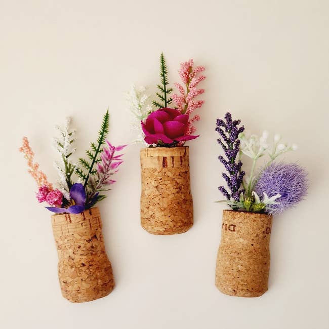 three magnets that look like mini flowers in cork vases
