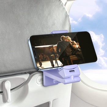 the purple phone mount attached to an airplane seat-back tray holding a phone that's showing a movie