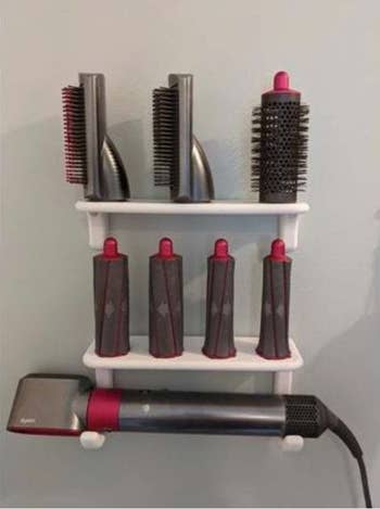 two shelves with hair attachments and the dryer on the bottom on hooks