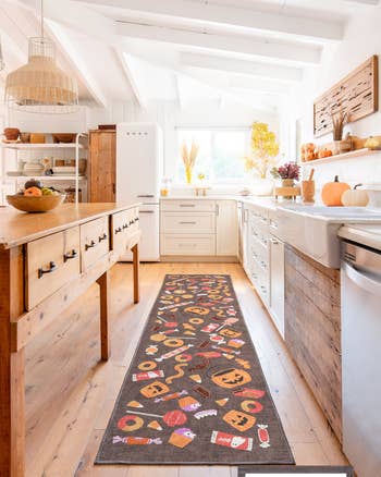 Stylish, rustic room  with a long, decorative rug featuring autumn-themed patterns and a farmhouse-style decor, including pumpkins and woody  accents