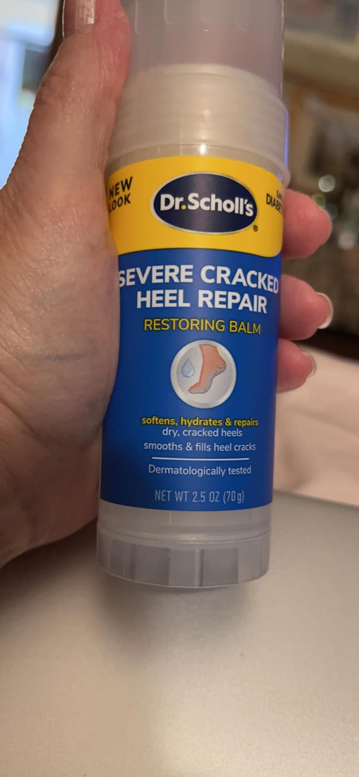 Hand holding Dr. Scholl's Severe Cracked Heel Repair balm for dry, cracked heels
