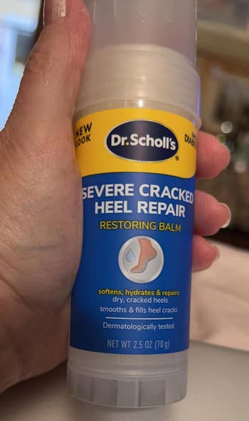 Hand holding Dr. Scholl's Severe Cracked Heel Repair balm for dry, cracked heels