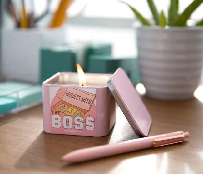 The pink biscuits with the boss candle lit up, on a desk surrounded by office accessories