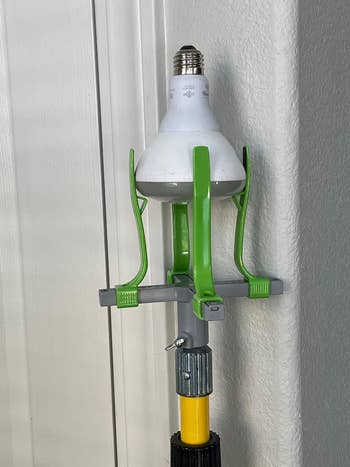 LED bulb mounted on a gray and green adjustable lamp holder attached to a yellow pole