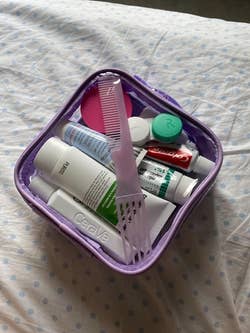 reviewer's lilac bag full of all the toiletry items and zipped shut