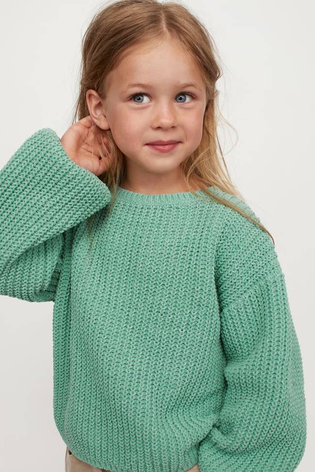 a child in an oversized green sweater with balloon sleeves