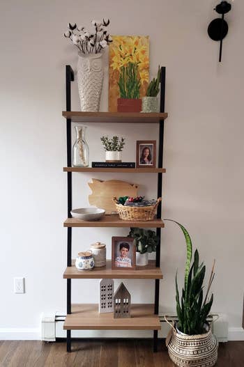 another reviewers oak and black 5-tier shelf holding carious plants, photos, and knickknacks