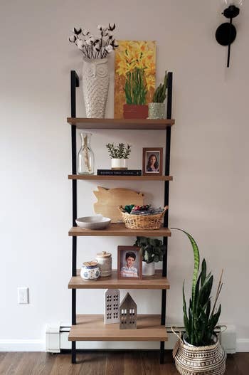 another reviewers oak and black 5-tier shelf holding carious plants, photos, and knickknacks