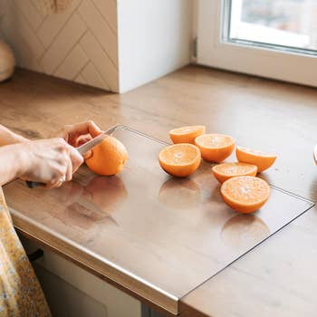 model slicing an orange on acrylic cutting board