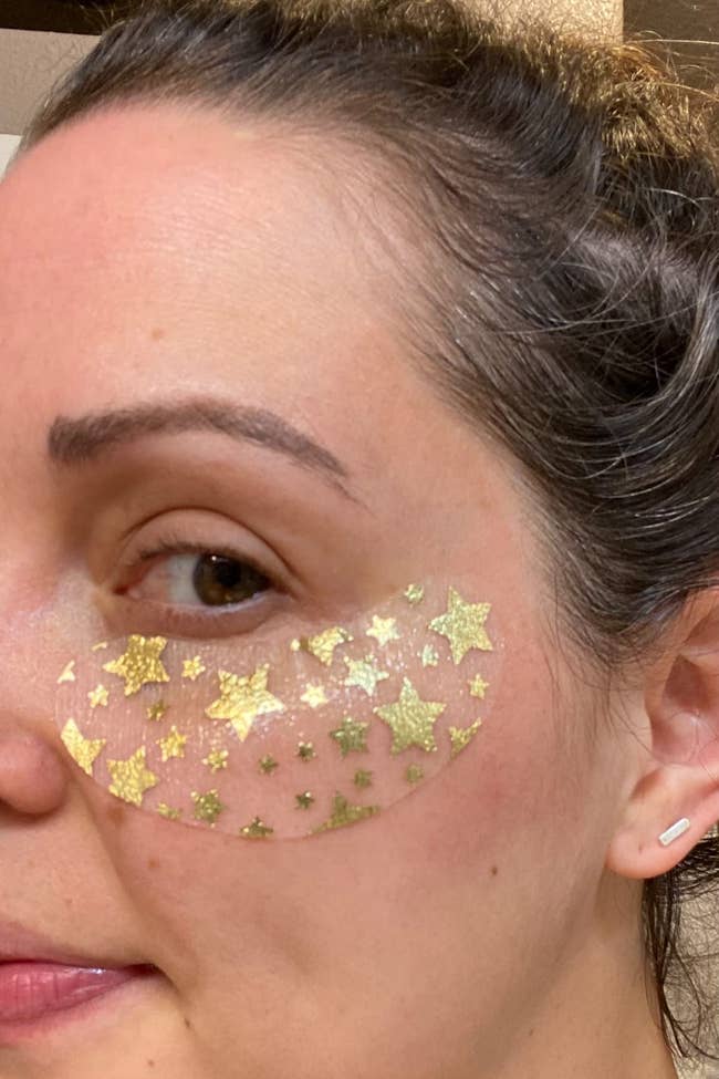 reviewer wearing under eye mask with gold star print on it