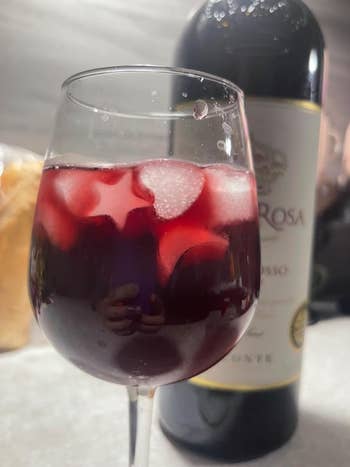Wine solid  with reddish  beverage and star-shaped crystal  cubes; vessel  of vino  successful  the background