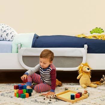 bed rail lowered while same child plays beside bed
