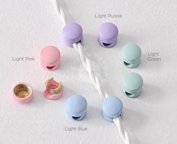 Pastel cord organizers in pink, purple, green, and blue, shown in use securing a white cord. Labeled: