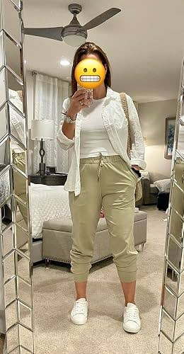 Person successful  casual wear, including a achromatic  shirt, airy  pants, and sneakers, takes a reflector  selfie successful  a modern   surviving  room