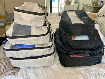 Two stacks of packing cubes successful  antithetic  sizes are neatly arranged connected  a bed, showcasing an organized question   packing solution