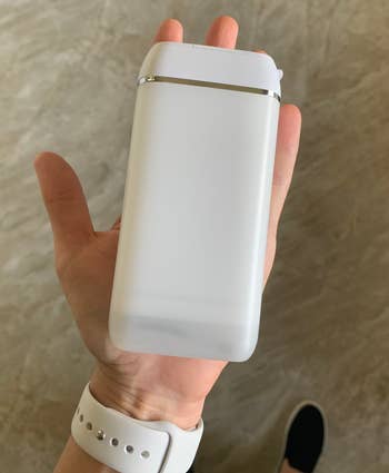 Reviewer holding a sleek, rectangular white water floss in one hand