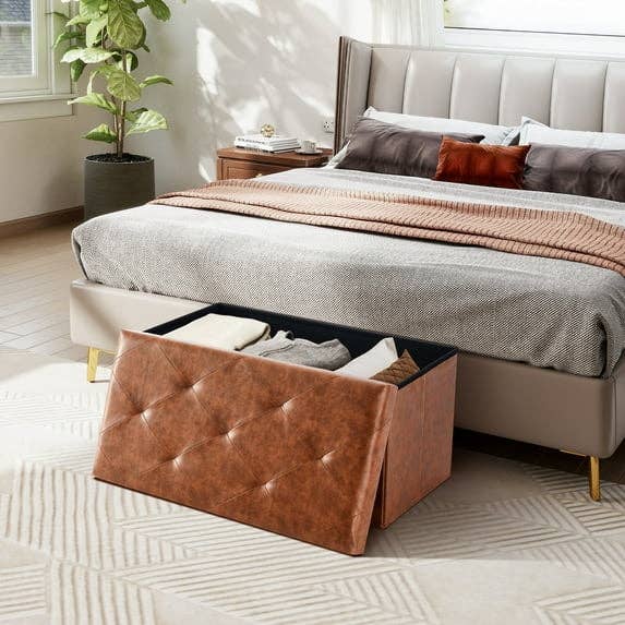 Tufted retention seat with unfastened lid, showcasing neatly folded clothes, placed astatine the ft of a modern furniture successful a stylish bedroom