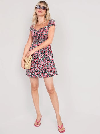 a model in a pink floral mini dress with a cap sleeve