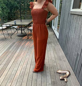 reviewer posing on deck in rust orange jumpsuit