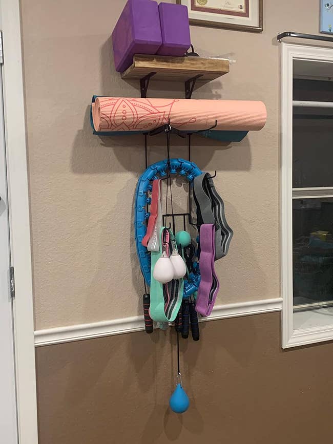 reviewer image of a yoga mat holder with a yoga mat, foam rollers, and resistance bands
