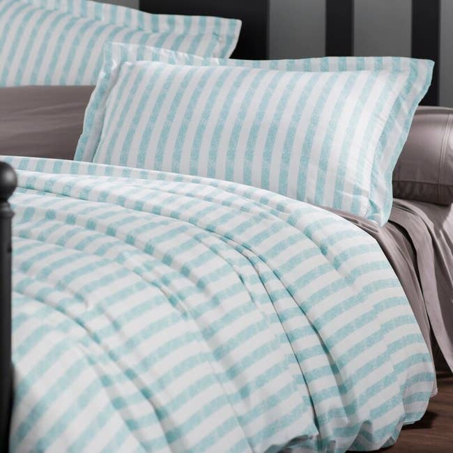 A blue striped comforter and pillows on bed