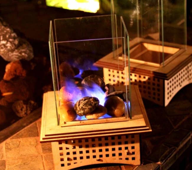 A lit mini glass fireplace with fire and stones
