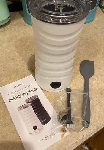 a reviewer photo of the milk frother in white with the included attachments 