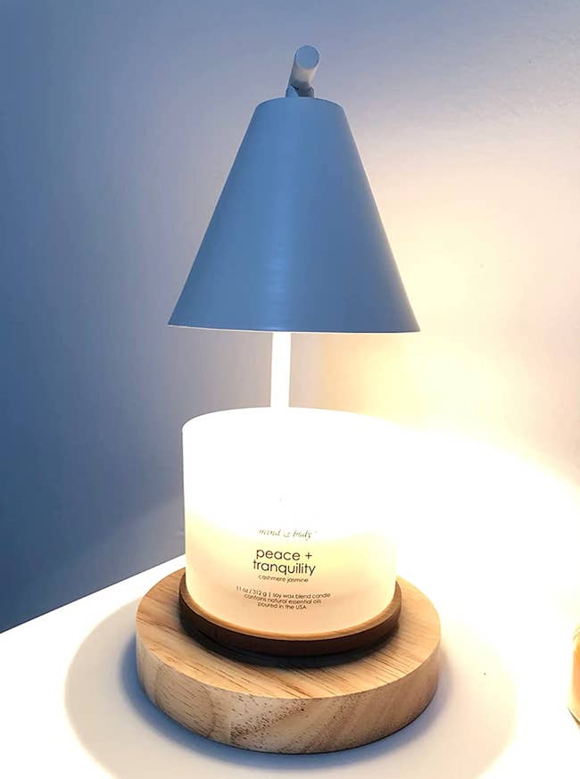 A lamp with a wooden base warming a melting candle 