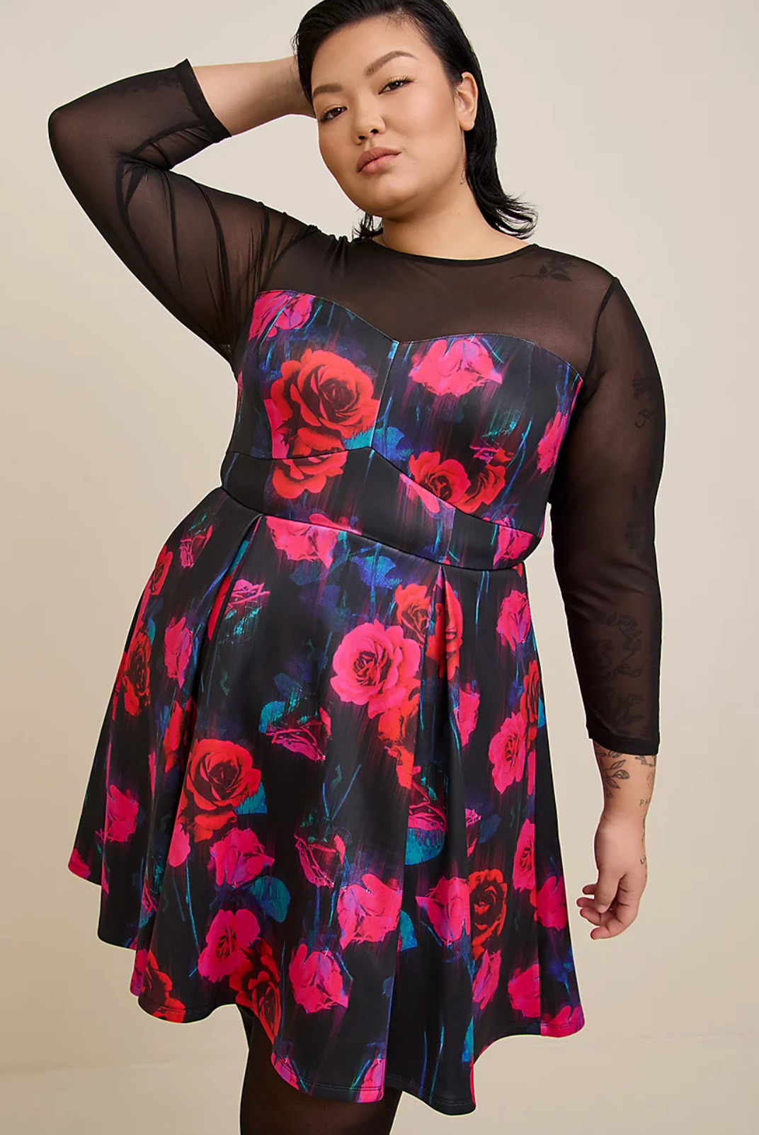 A model wearing the dress with a rose design and black mesh sleeves