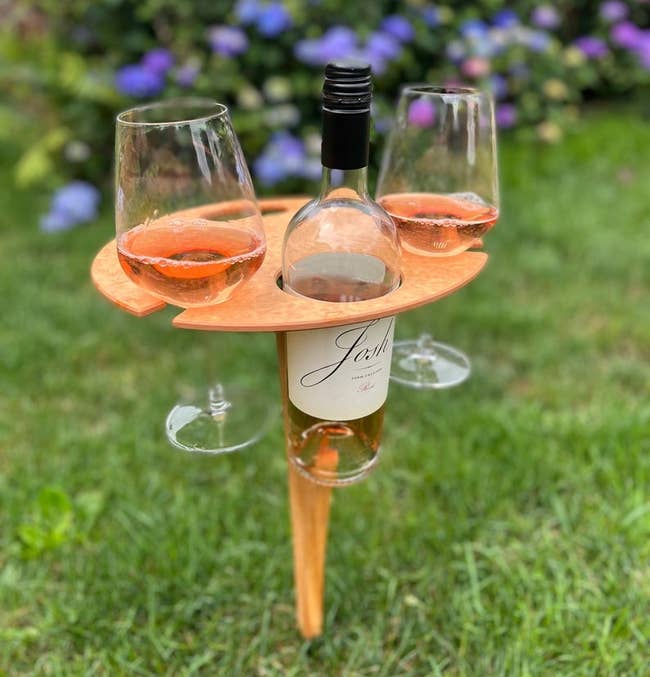 the folding wine table in the grass holding a bottle and two glasses