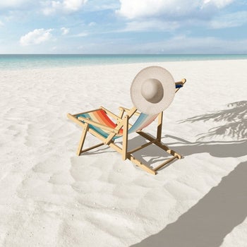the retro printed sling chair staged on a beach with a hat hanging off of it