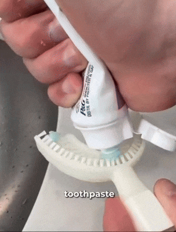 A person squeezes a tube of toothpaste onto a toothbrush with the label