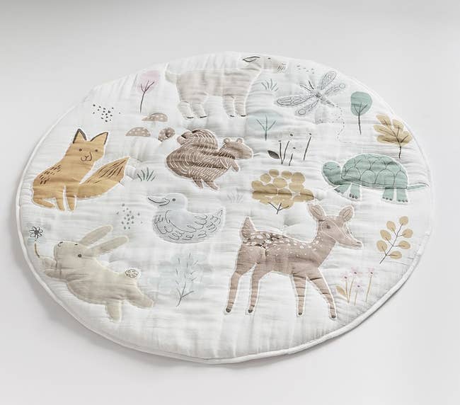 a round muslin play mat with animals stitched into it