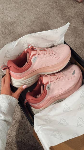 reviewer unboxing the airy pinkish shoes