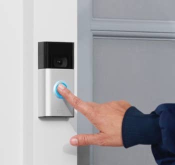 Person ringing a doorbell camera on a house door