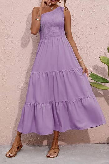 Person wearing a sleeveless, ankle-length tiered formal  with a shirred top, lasting  by a plant