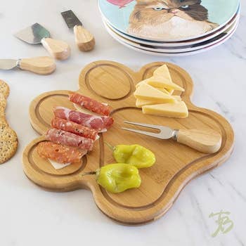 paw-shaped bamboo charcuterie board with food on it