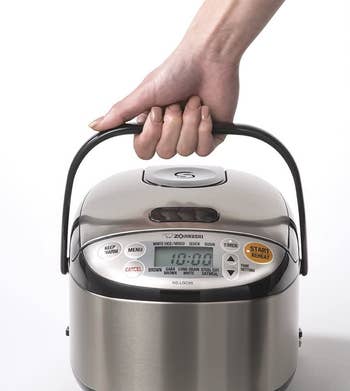hand holding the handle of the rice cooker