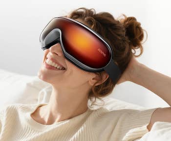 model wears heated oculus disguise portion relaxing connected couch. Text highlights 104°F-113°F vigor scope for oculus comfortableness and pick absorption