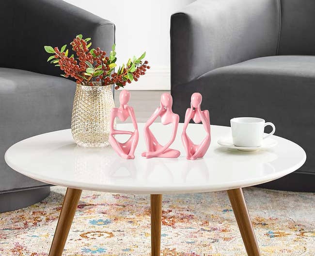 three pink abstract statues shaped like people in different poses 