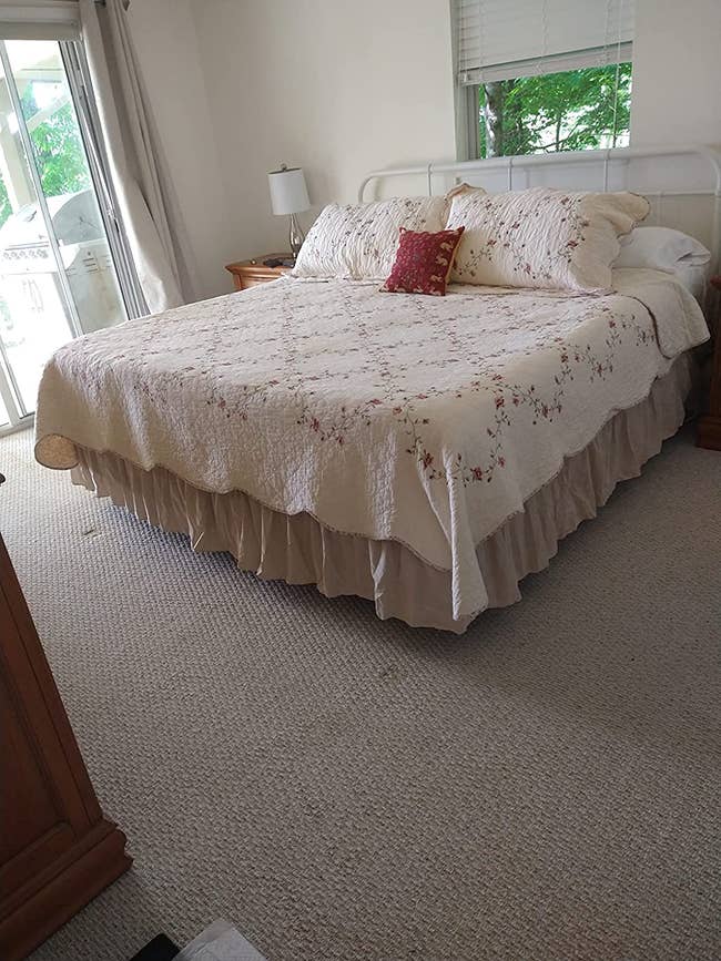 Reviewer pic of the white dust ruffle on their bed