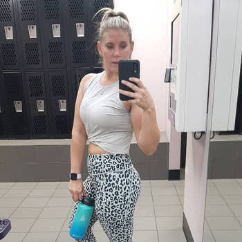 reviewer gym mirror selfie wearing white twist-front crop top and leopard print leggings
