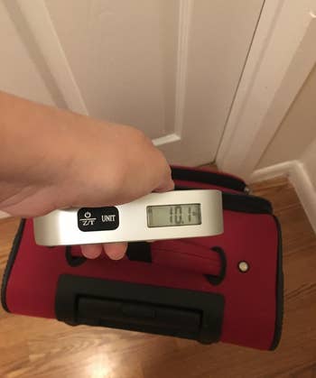 reviewer's luggage with scale on it reading the weight