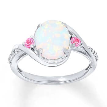 opal oval in center of silver band with little pink stones and  silver diamonds around it