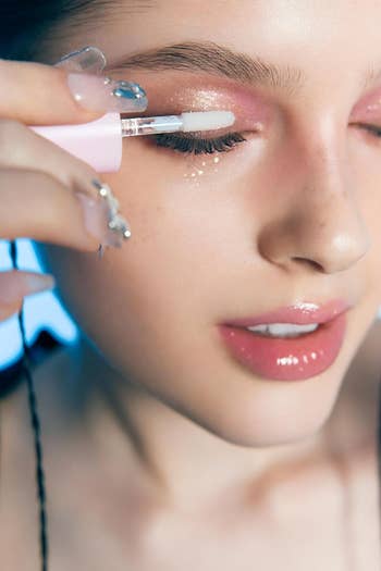 Close-up of a idiosyncratic   applying shimmery oculus  constitution  with a brush, showcasing quality   and constitution  application