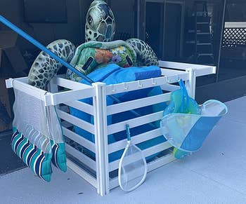 reviewer photo of the organizer holding pool toys and pool cleaning supplies