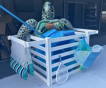 reviewer photo of the organizer holding pool toys and pool cleaning supplies